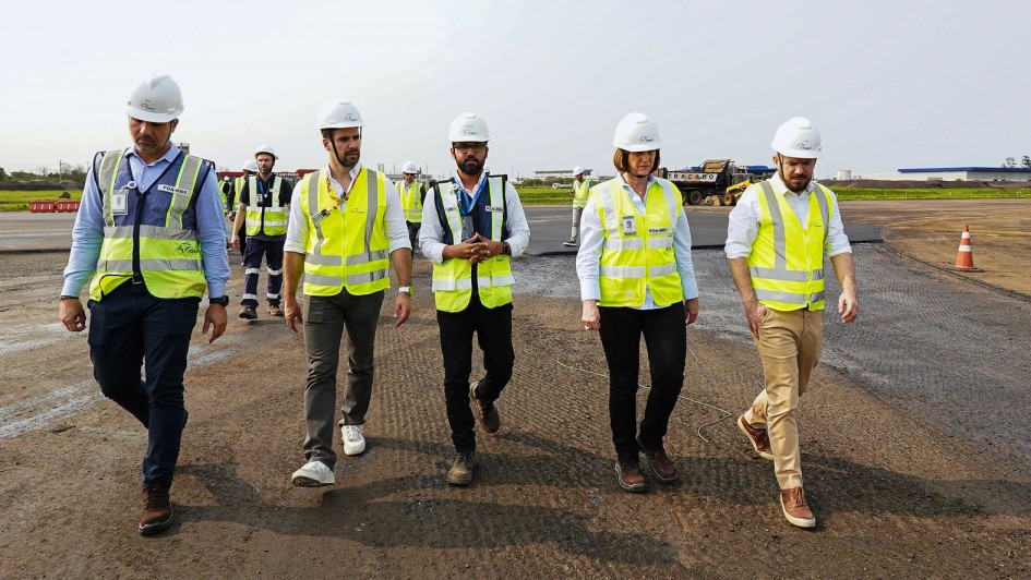 Leite caminhando acompanhado de quatro pessoas enquanto vistoria obras na pista do aeroporto Salgado Filho.